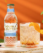 Double Dutch bottle of Skinny Tonic Water with a cocktail on an orange background