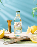 Double Dutch ELDERFLOWER TONIC WATER mixer bottle with lemons and a jigger on a table