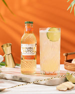 Double Dutch ginger ale mixer bottle with a glass of ginger ale on an orange background